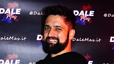 Ritratto sorridente di Gio Salsatero, insegnante di salsa cubana presso Il Mosaico Danza a Milano, con maglietta nera e sfondo scuro brandizzato